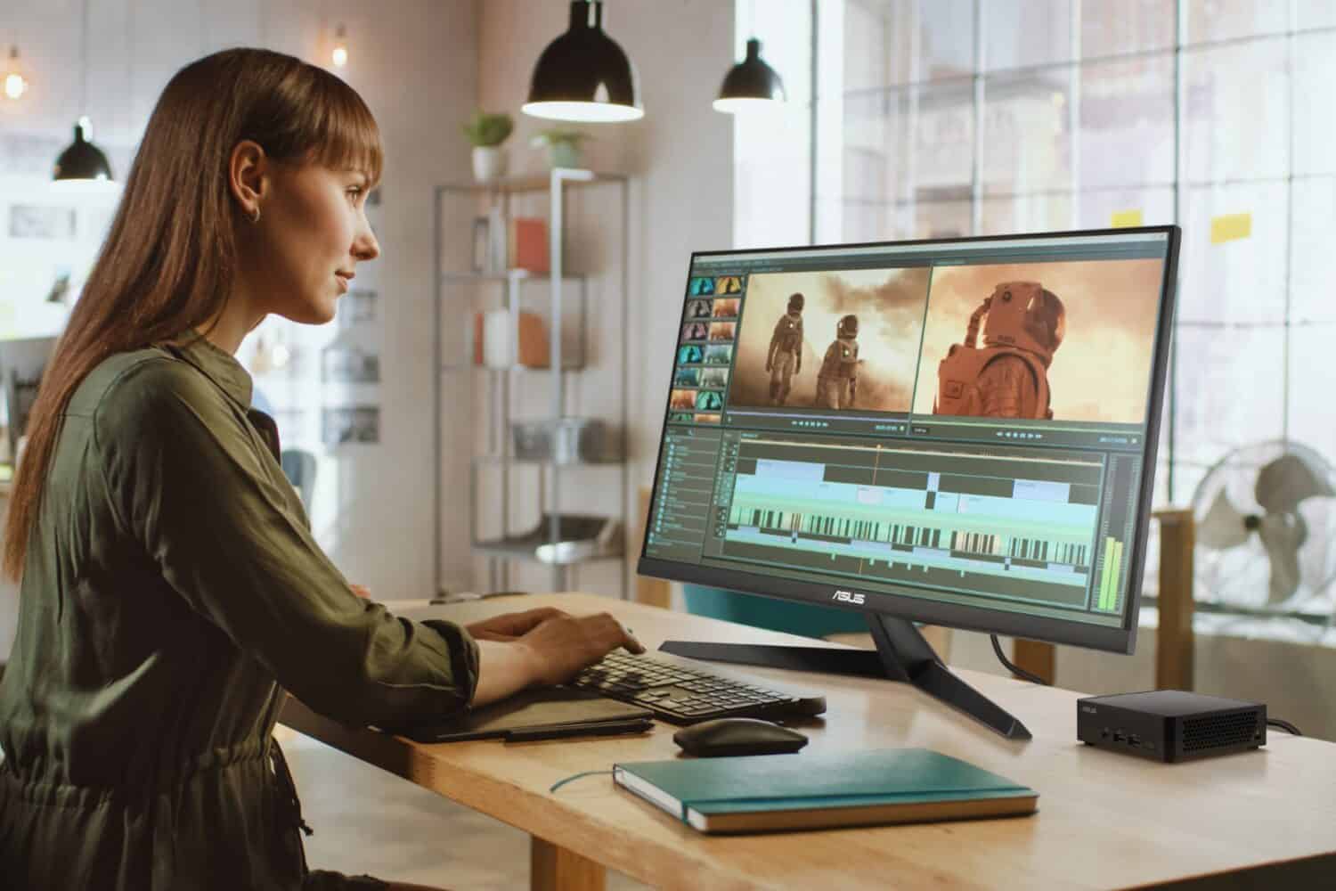Beautiful,And,Creative,Brunette,Female,Video,Editor,Works,With,Footage Een vrouw werkt aan videobewerking aan een bureau met een groot scherm waarop scènes en een tijdlijn worden weergegeven. De kamer heeft moderne verlichting en grote ramen.